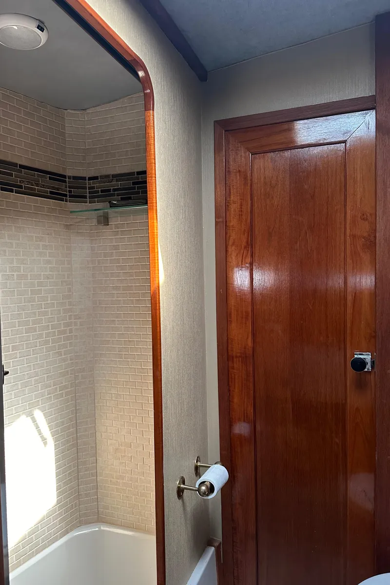 Slide: The Image of 1987 Bayliner 3888 Motoryacht bathroom with wood door and tiled shower. - 20