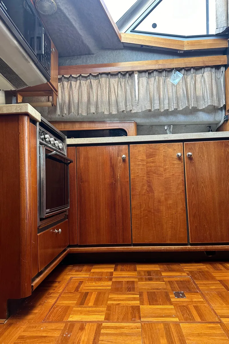 Slide: The Image of 1987 Bayliner 3888 Motoryacht kitchen with wood cabinets and parquet flooring. - 23