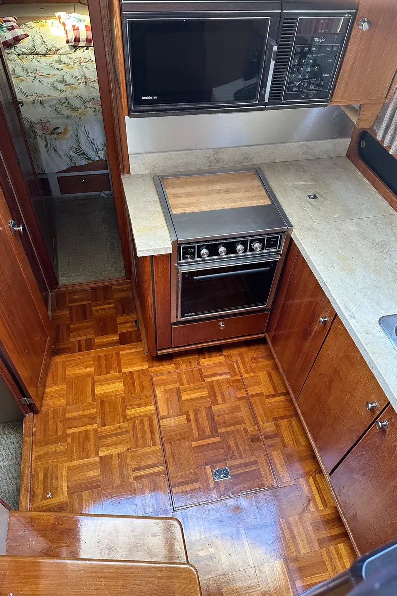 Slide: The Image of 1987 Bayliner 3888 Motoryacht kitchen with wood flooring, stove, and microwave. - 24