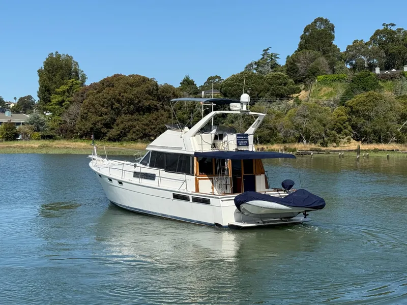 Slide: The Image of 1987 Bayliner 3888 Motoryacht on serene water, surrounded by lush greenery. - 27