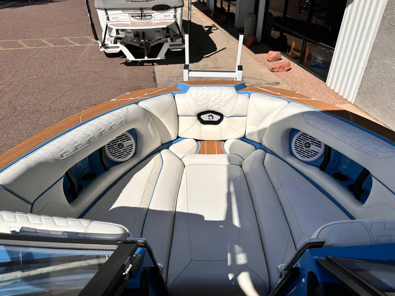 Slide: The Image of 2024 Centurion Ri265 boat interior with white and blue seating, speakers, and cup holders. - 12