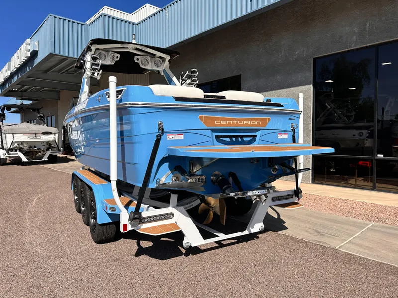 Slide: The Image of 2024 Centurion Ri265 boat in blue on a trailer outside a dealership. - 3