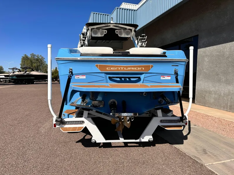 Slide: The Image of 2024 Centurion Ri265 boat, rear view, blue exterior, parked outdoors. - 4