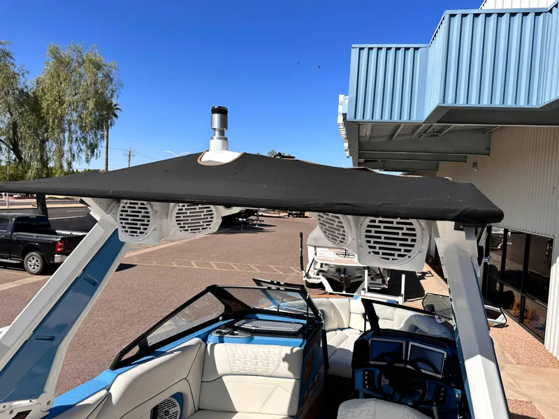 Slide: The Image of 2024 Centurion Ri265 boat with black canopy and white speakers in parking lot. - 8