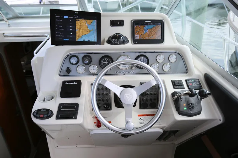Slide: The Image of 2005 Wellcraft 330 Coastal boat helm with navigation screens and controls. - 11