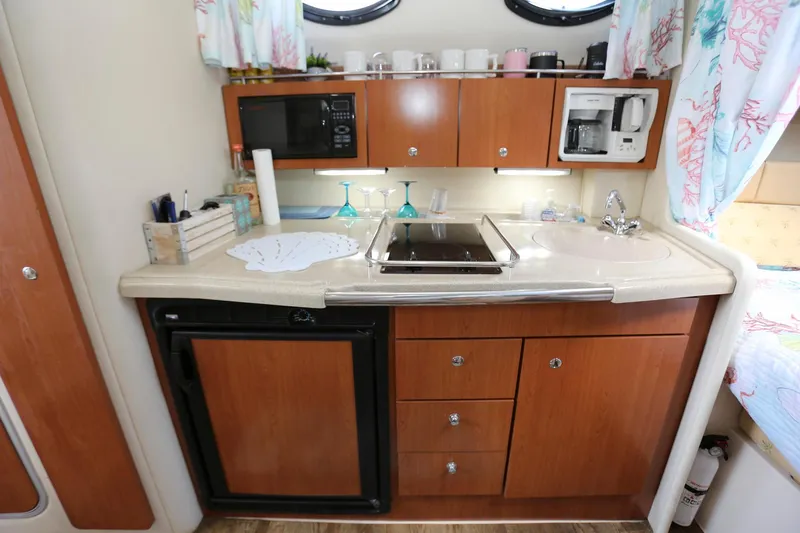 Slide: The Image of 2005 Wellcraft 330 Coastal boat kitchen with microwave, stove, sink, and storage cabinets. - 19