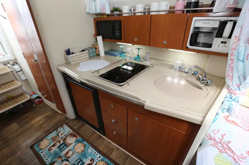Slide: The Image of 2005 Wellcraft 330 Coastal boat kitchen with sink, stove, microwave, and storage cabinets. - 20
