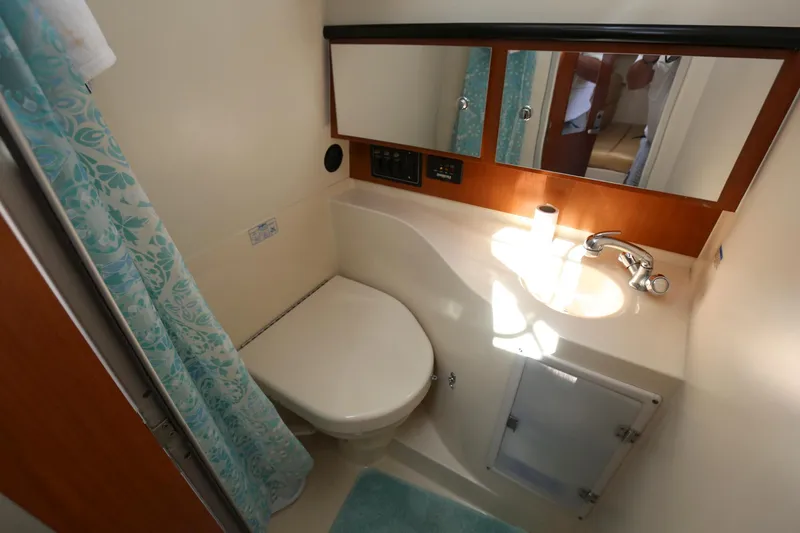 Slide: The Image of 2005 Wellcraft 330 Coastal bathroom with toilet, sink, mirror, and shower curtain. - 24