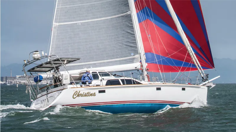 Slide: The Image of Sailing yacht "Christina" on the water, featuring vibrant red and blue sails. - 0