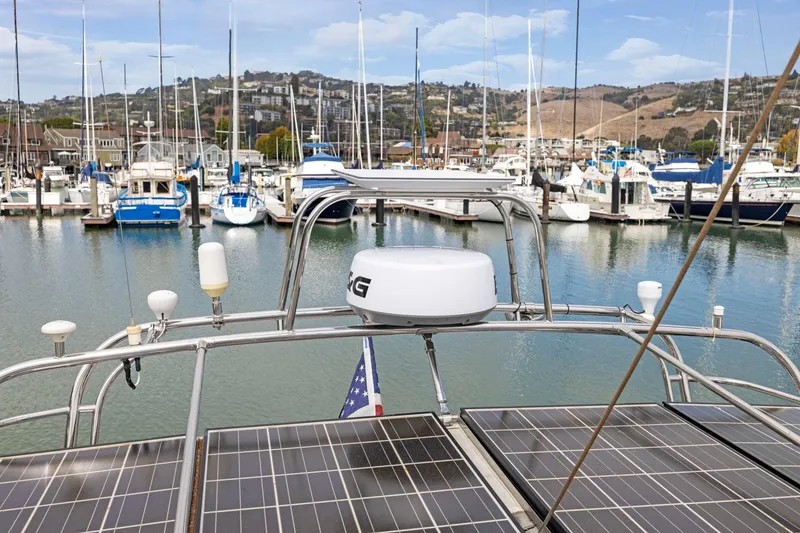 Slide: The Image of Boat with solar panels docked in marina, surrounded by other boats, hills in background. - 23