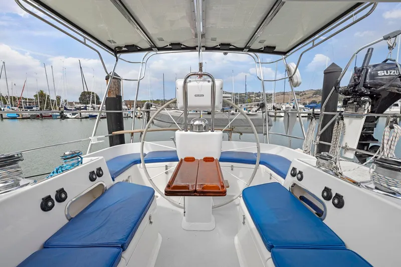 Slide: The Image of Sailboat cockpit with blue cushions, wooden table, and marina view; Morris 486, 2005 model. - 25