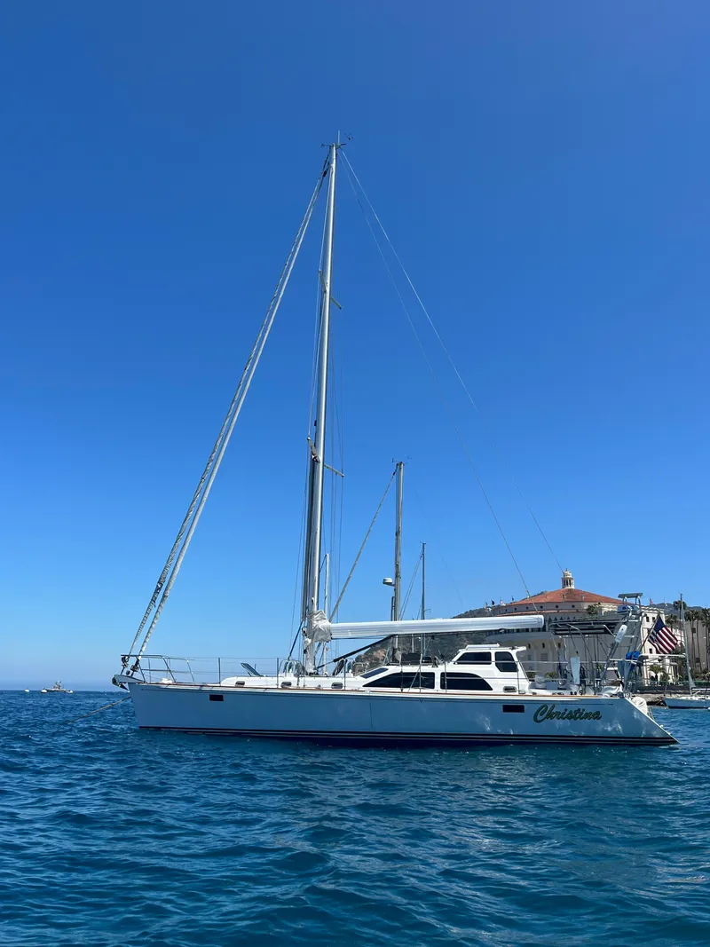 Slide: The Image of Sailboat Morris 486 (2005) on blue ocean near coastal town under clear sky. - 49