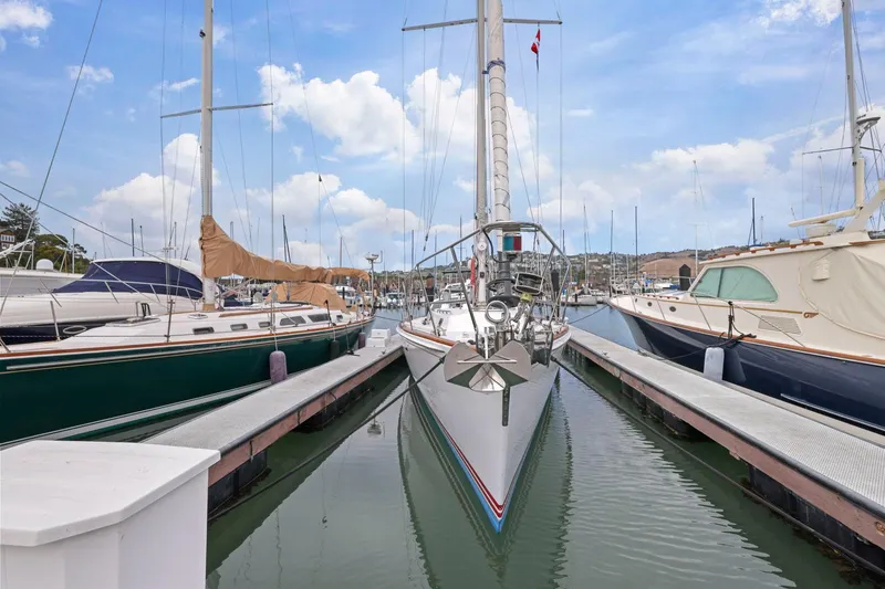 Slide: The Image of Sailboat docked in marina, surrounded by other boats, under a clear blue sky. - 5