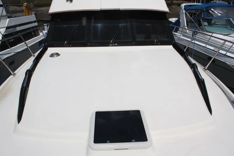 Slide: The Image of 1986 Birchwood 42 Empress yacht deck with windshield and hatch, docked alongside other boats. - 10