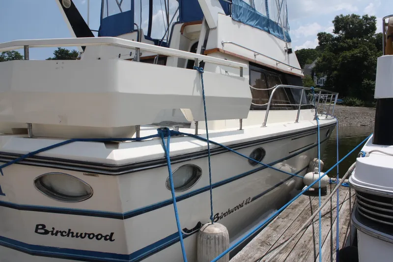 Slide: The Image of 1986 Birchwood 42 Empress yacht docked, featuring classic design and blue accents. - 2