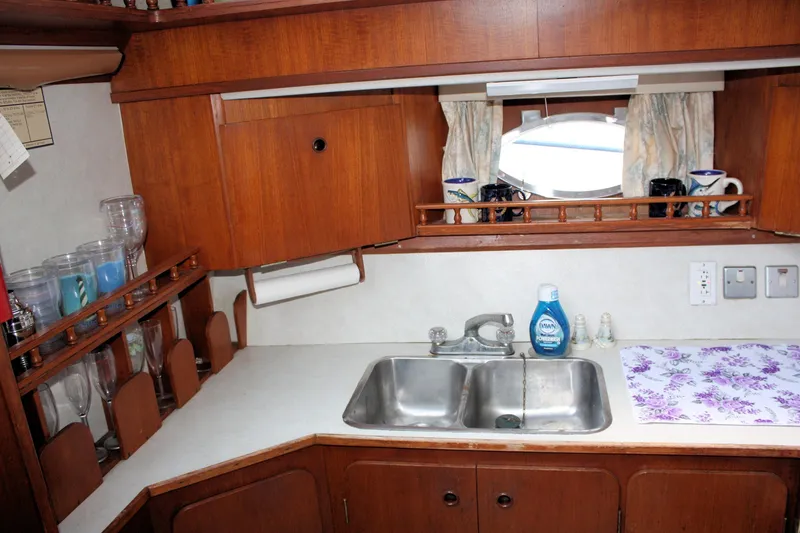 Slide: The Image of 1986 Birchwood 42 Empress yacht kitchen with wooden cabinets, double sink, and countertop accessories. - 32