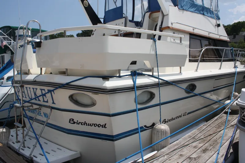 Slide: The Image of 1986 Birchwood 42 Empress yacht docked, featuring blue accents and mooring lines. - 4