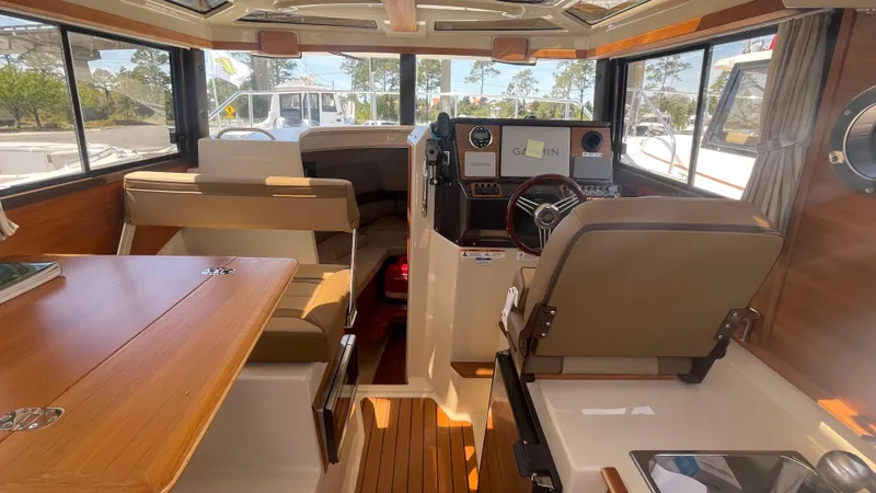 Slide: The Image of 2024 Ranger Tugs R-25 interior with helm, seating, and wooden accents. - 17