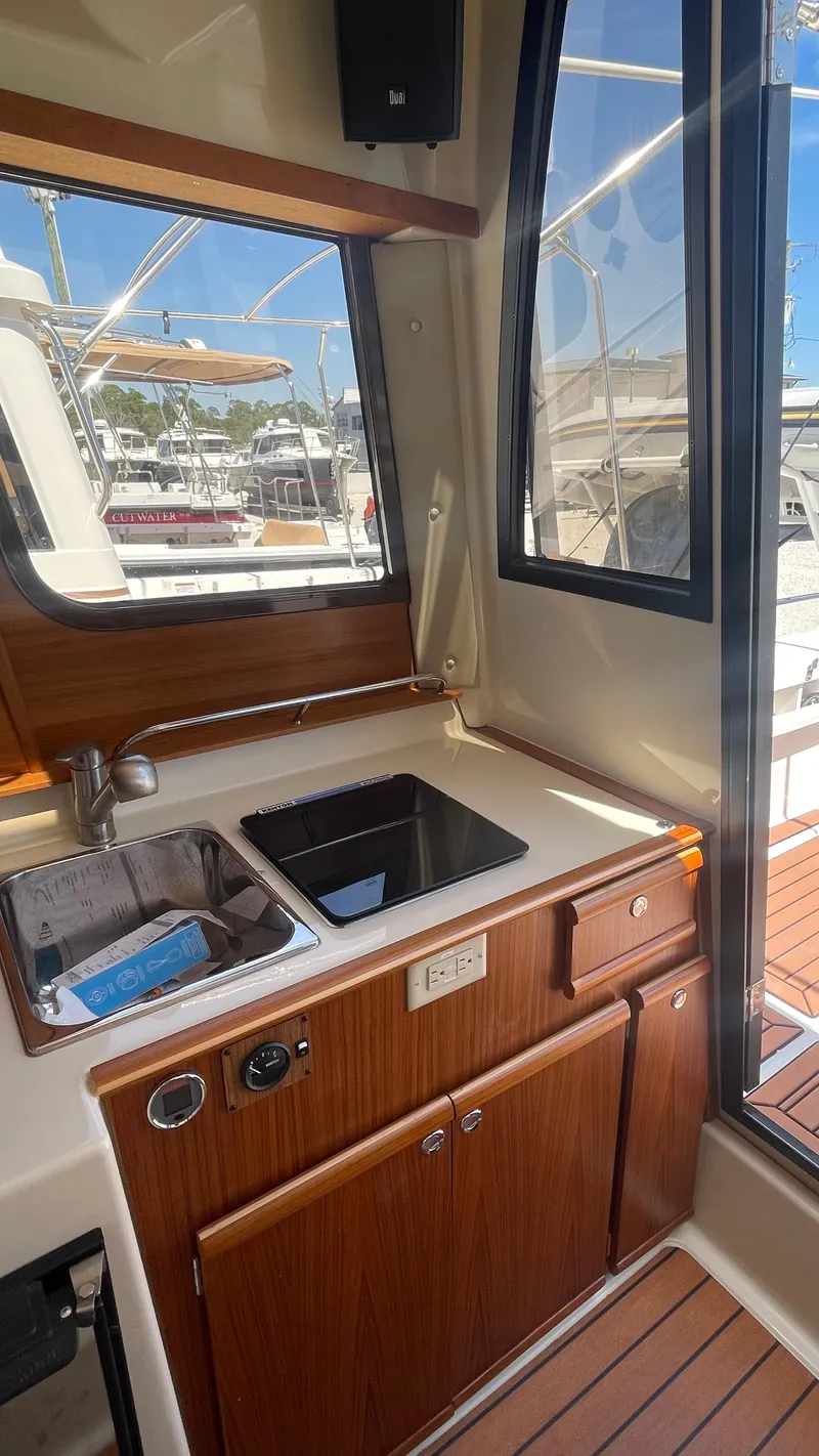 Slide: The Image of 2024 Ranger Tugs R-25 interior kitchen with sink and wooden cabinetry. - 20