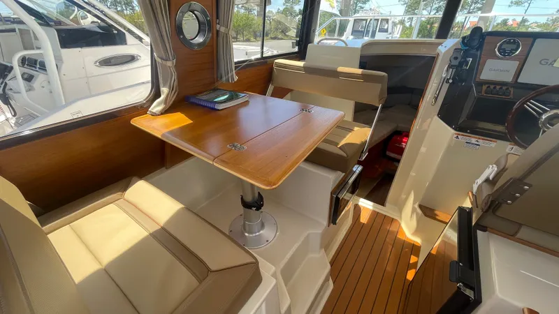 Slide: The Image of 2024 Ranger Tugs R-25 interior with wood table, seating, and navigation equipment. - 21
