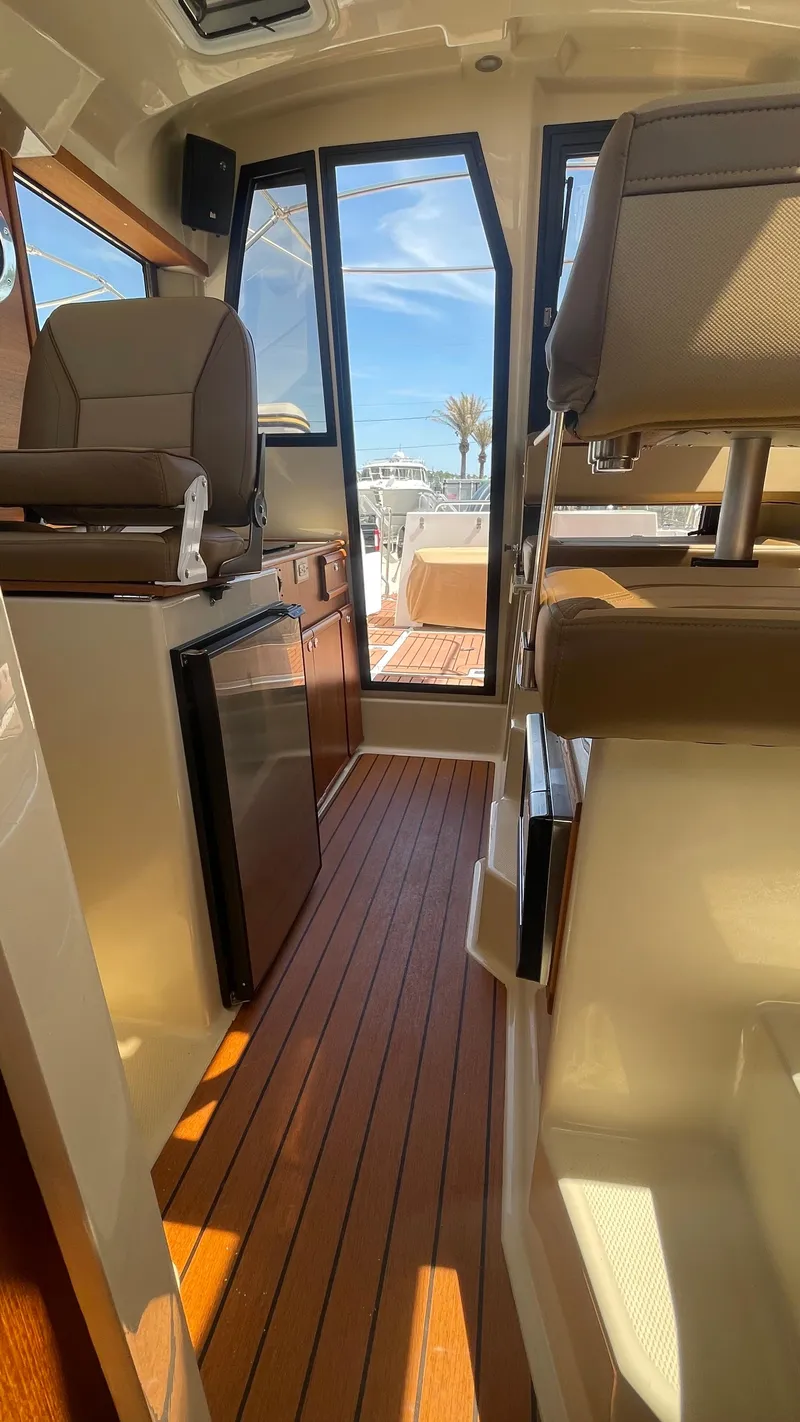 Slide: The Image of 2024 Ranger Tugs R-25 interior with wood flooring and seating, showcasing modern design. - 24