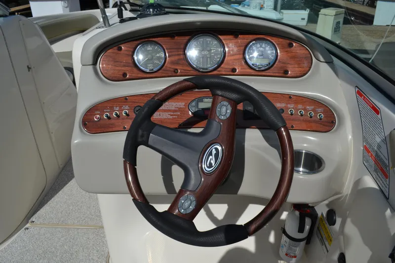 Slide: The Image of 2005 Sea Ray 240 Sundeck dashboard with wood trim and steering wheel. - 9