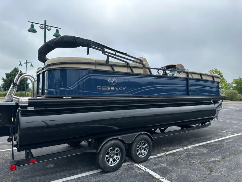 Slide: The Image of 2024 Regency 230 DL3 pontoon boat on trailer in parking lot. - 2
