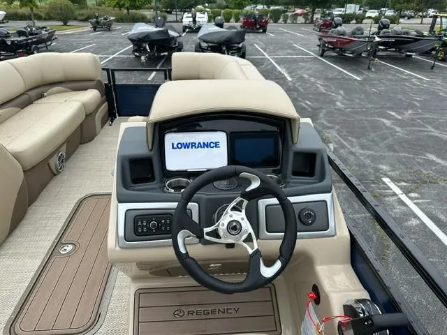 Slide: The Image of 2024 Regency 230 DL3 boat dashboard with Lowrance navigation system in parking lot. - 8