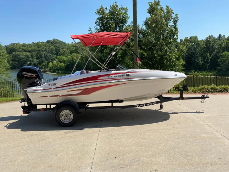 The Image of 2024 Tahoe T16 boat with red canopy on trailer, parked outdoors. - 0