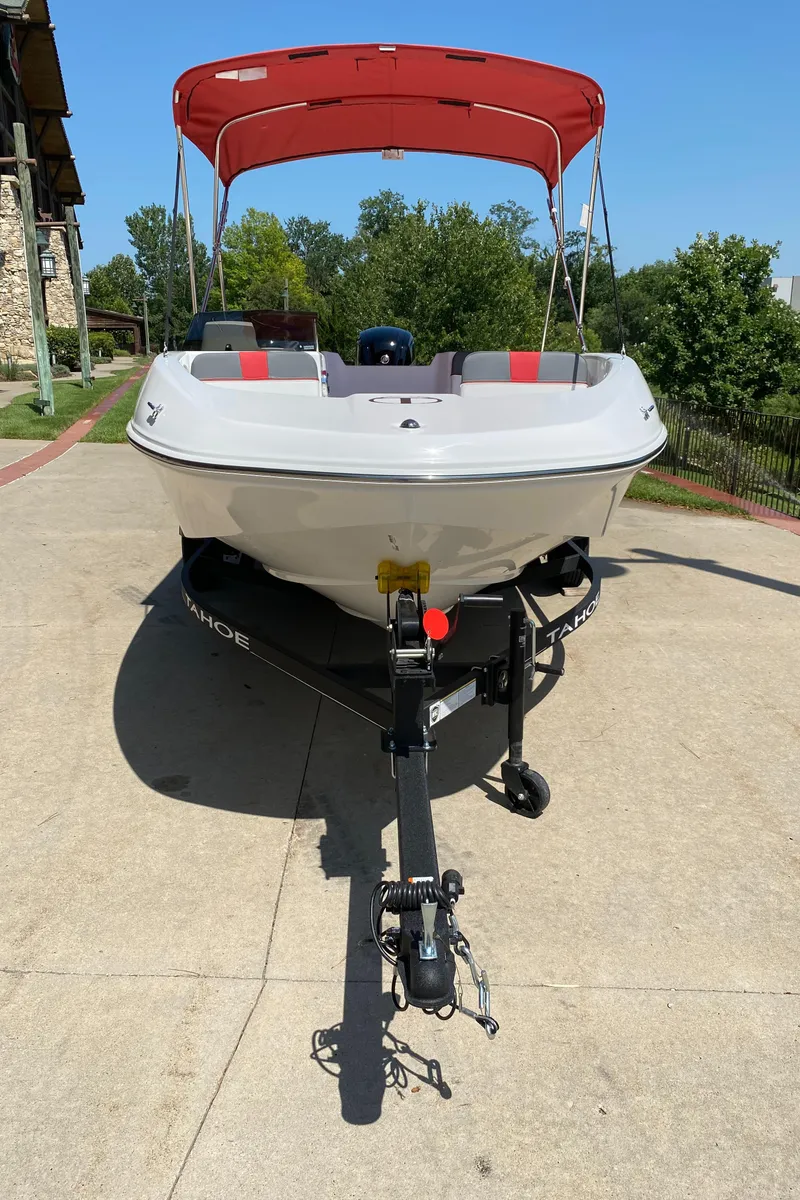 Slide: The Image of 2024 Tahoe T16 boat with red canopy on trailer, parked outdoors. - 2