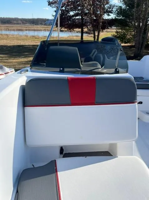 Slide: The Image of 2024 Tahoe T18 boat interior with gray and red seating, near a lake. - 2
