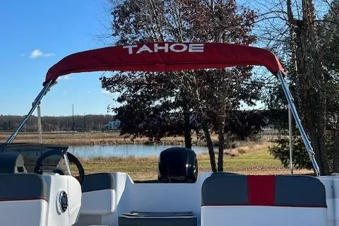 Slide: The Image of 2024 Tahoe T18 boat with red canopy, parked near a serene lake. - 8
