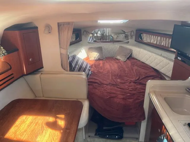 Slide: The Image of Interior cabin of a 2005 Sea Ray 280 Sundancer with bed, table, and kitchenette. - 19