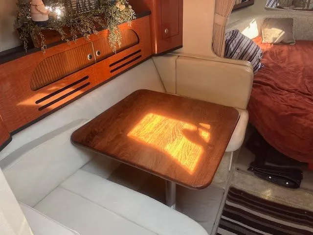Slide: The Image of 2005 Sea Ray 280 Sundancer interior dining area with wooden table and white seating. - 20