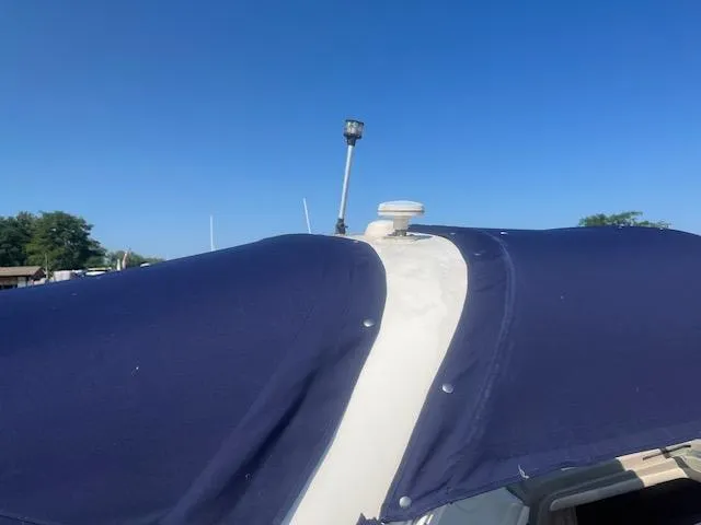 Slide: The Image of 2005 Sea Ray 280 Sundancer with blue canvas cover under clear sky. - 6