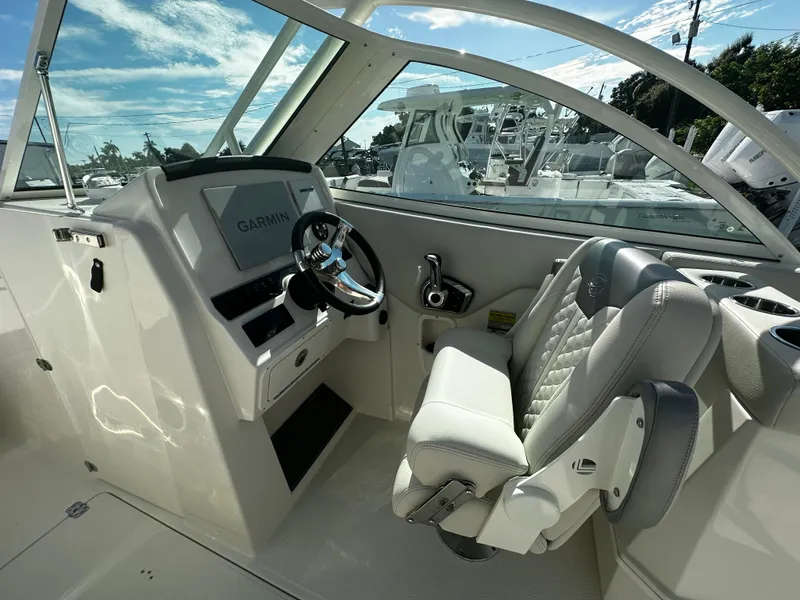 Slide: The Image of 2025 Sailfish 245 DC boat cockpit with Garmin navigation system and cushioned captain's chair. - 16