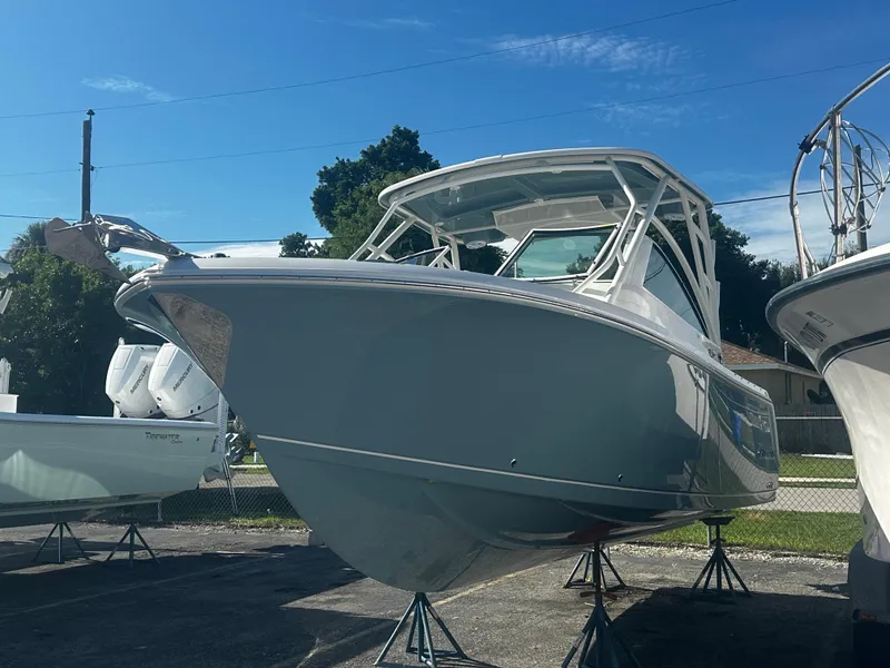 Slide: The Image of 2025 Sailfish 245 DC boat on stands in a marina under a clear blue sky. - 3