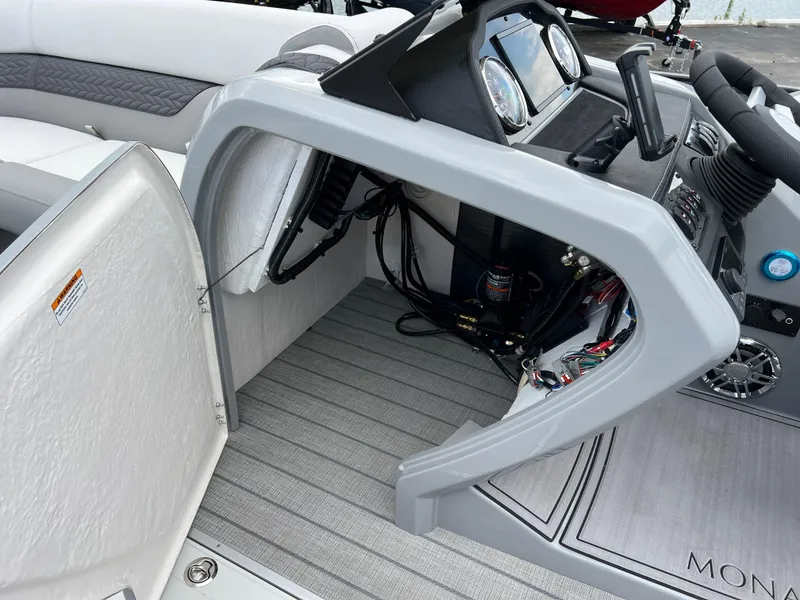 Slide: The Image of 2025 Godfrey Monaco 235 RL boat dashboard and open storage compartment. - 26