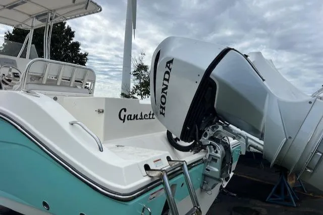 Slide: The Image of 2021 Cobia 237 Center Console with Honda outboard motor, teal and white design. - 7