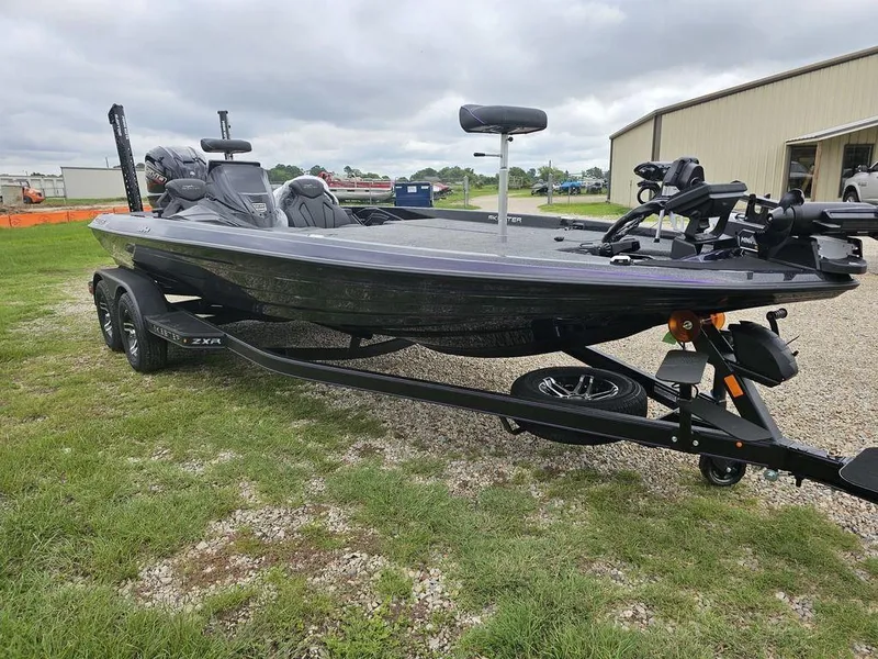 Slide: The Image of 2025 Skeeter ZXR21 bass boat on trailer, parked on grass. - 13