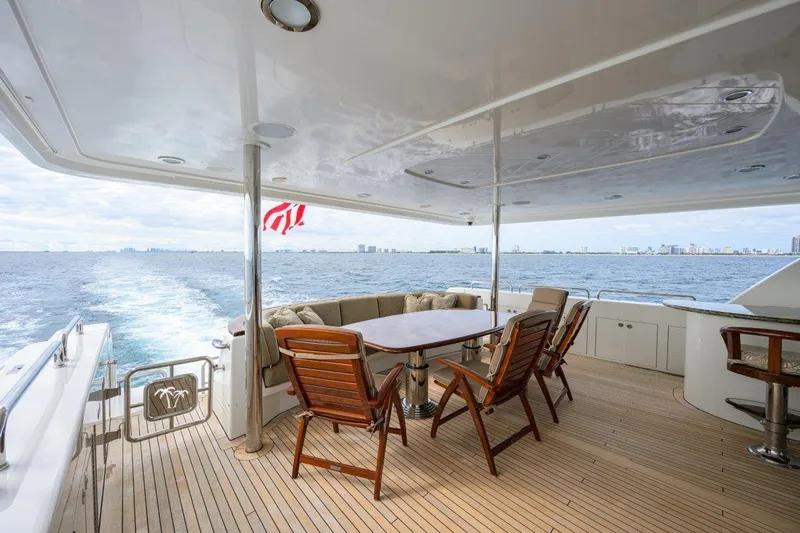 Slide: The Image of Luxurious 2008 Westport 112 yacht deck with dining area, ocean view, and wooden chairs. - 24