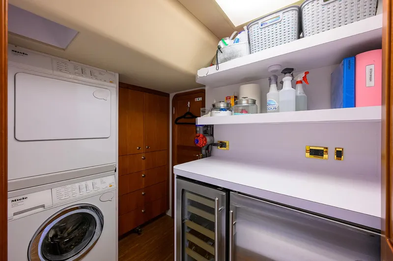 Slide: The Image of Laundry room with stacked washer-dryer, storage shelves, and cleaning supplies on a 2008 Westport 112 yacht. - 66