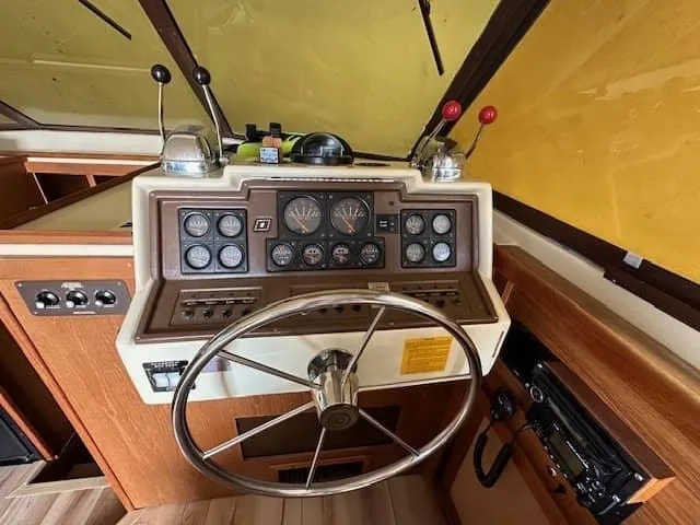 Slide: The Image of 1985 Trojan T36 boat helm with steering wheel, control panel, and gauges. - 13