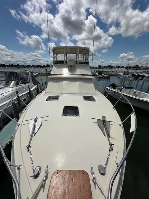 Slide: The Image of 1985 Trojan T36 boat docked at a marina under a partly cloudy sky. - 16