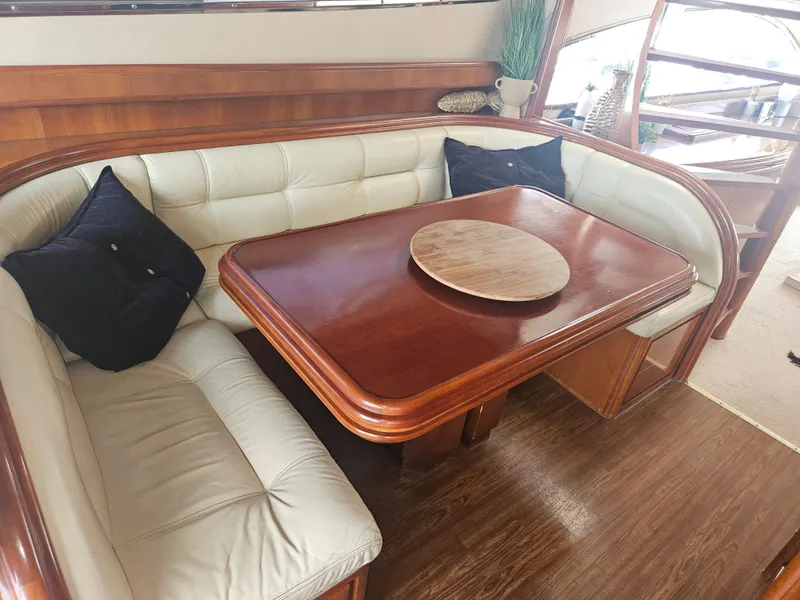 Slide: The Image of Luxurious seating area on 1998 Astondoa 72 GLX yacht with wooden table and cushioned benches. - 24