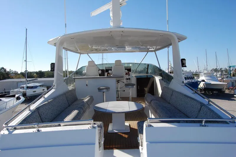 Slide: The Image of Hatteras 78 Aft Cockpit Motoryacht 1990, spacious upper deck with seating and table, docked at marina. - 5