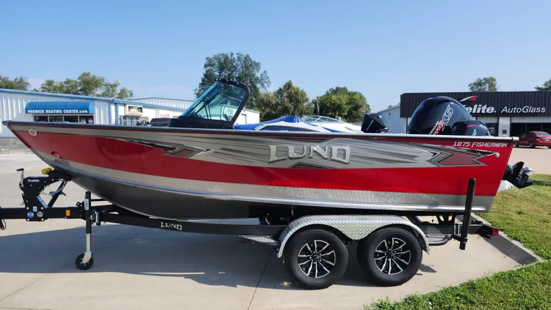 Slide: The Image of 2025 Lund 1875 Fisherman boat on trailer, red and silver design, parked outdoors. - 3