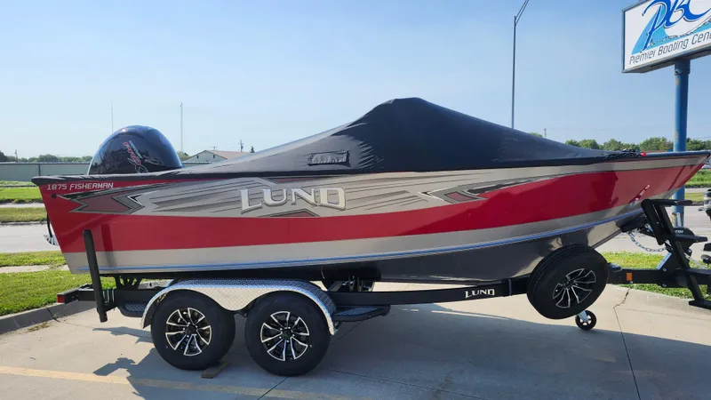Slide: The Image of 2025 Lund 1875 Fisherman boat on trailer, red and silver design, covered, parked outdoors. - 8