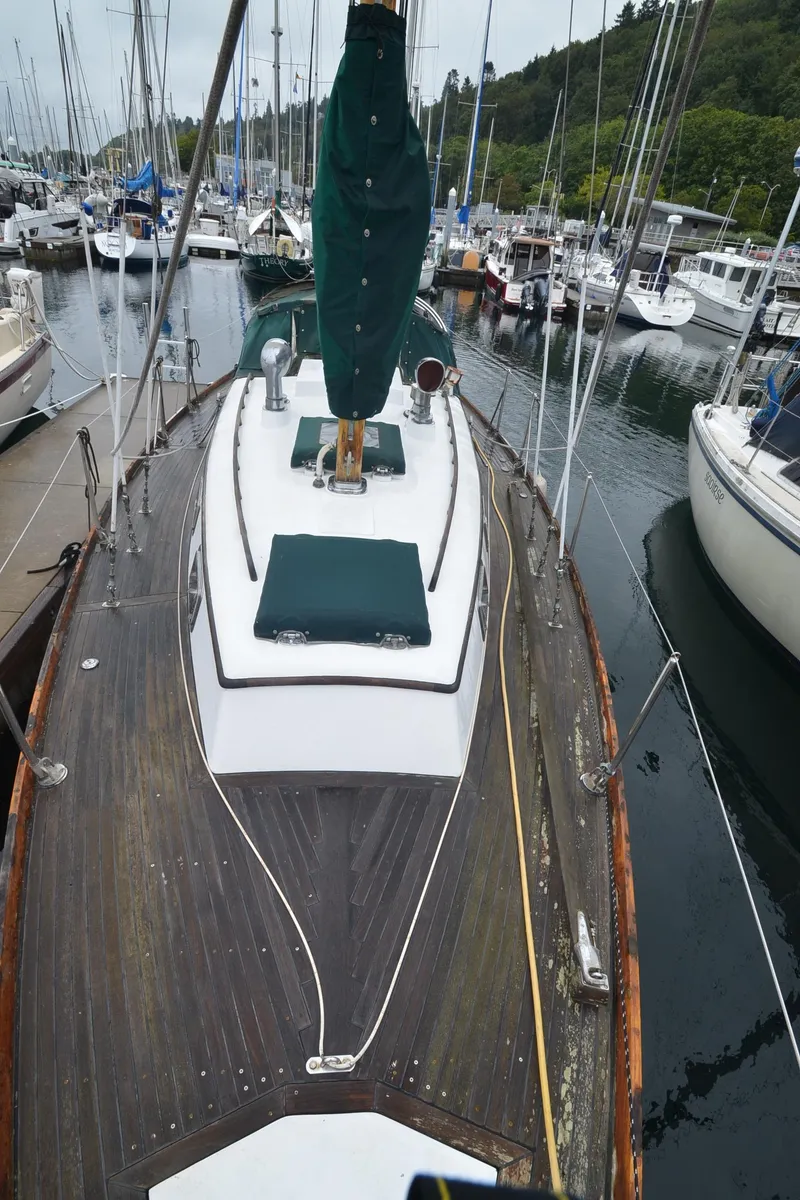Slide: The Image of 1978 Cheoy Lee Offshore 32 sailboat docked in a marina, featuring wooden deck and green sail cover. - 16