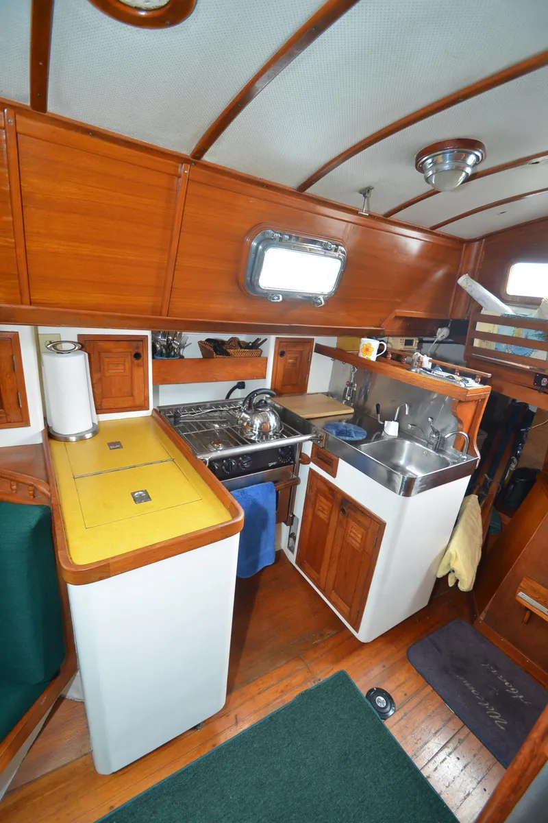 Slide: The Image of 1978 Cheoy Lee Offshore 32 yacht interior kitchen with wood cabinetry and compact appliances. - 27